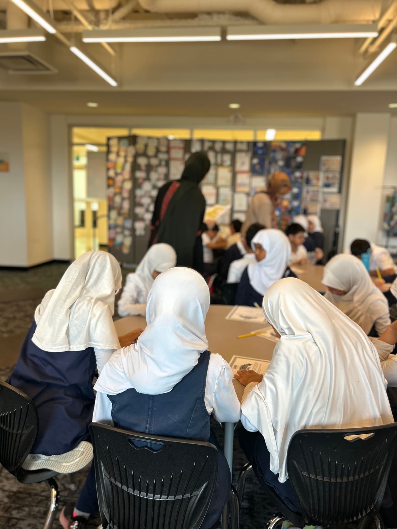 Students in white hijabs working together at classroom tables during an MVP workshop