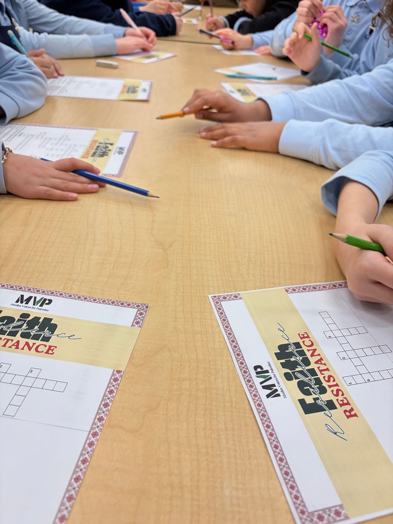 Students around a table filling in MVP “Faith & Resistance” crossword worksheets