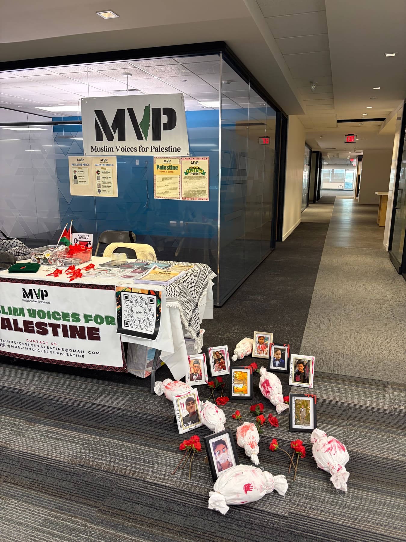 The MVP booth in a hallway with a memorial of framed photographs and roses laid out in front