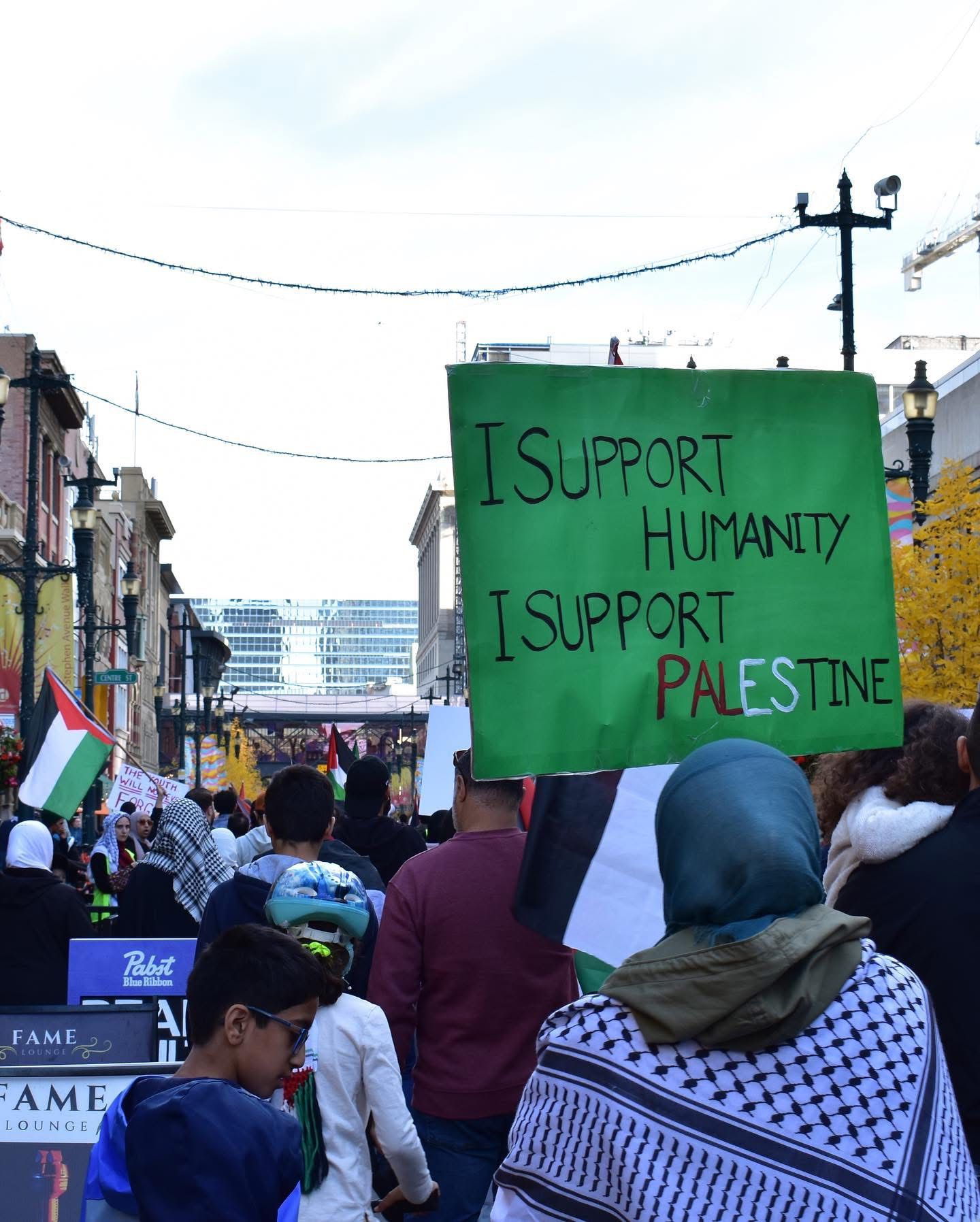 A marcher holding an “I support humanity, I support Palestine” sign on Stephen Avenue