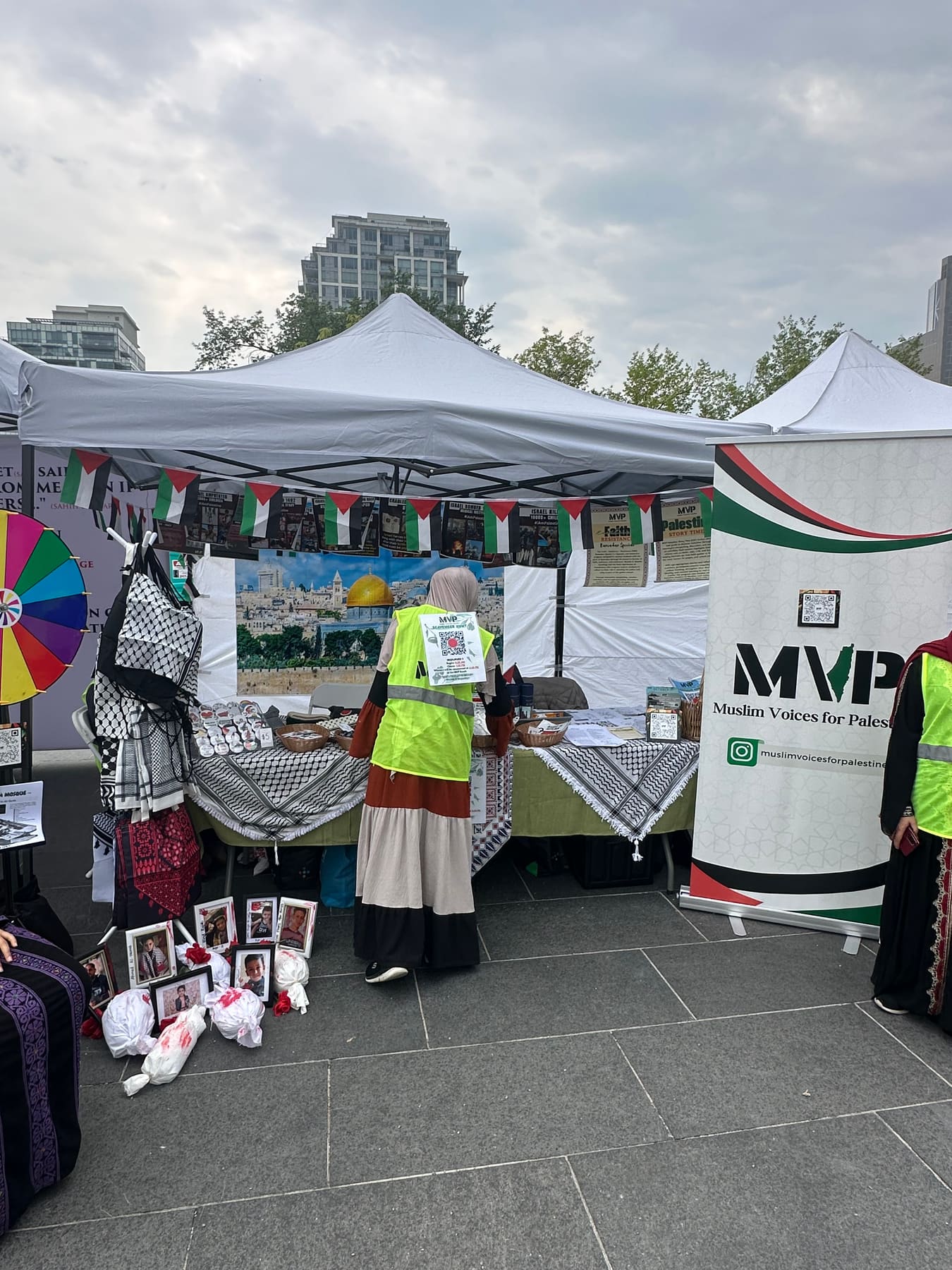 The MVP tent at Muslim Heritage Day with volunteers in green vests, a Jerusalem backdrop, and a prize wheel