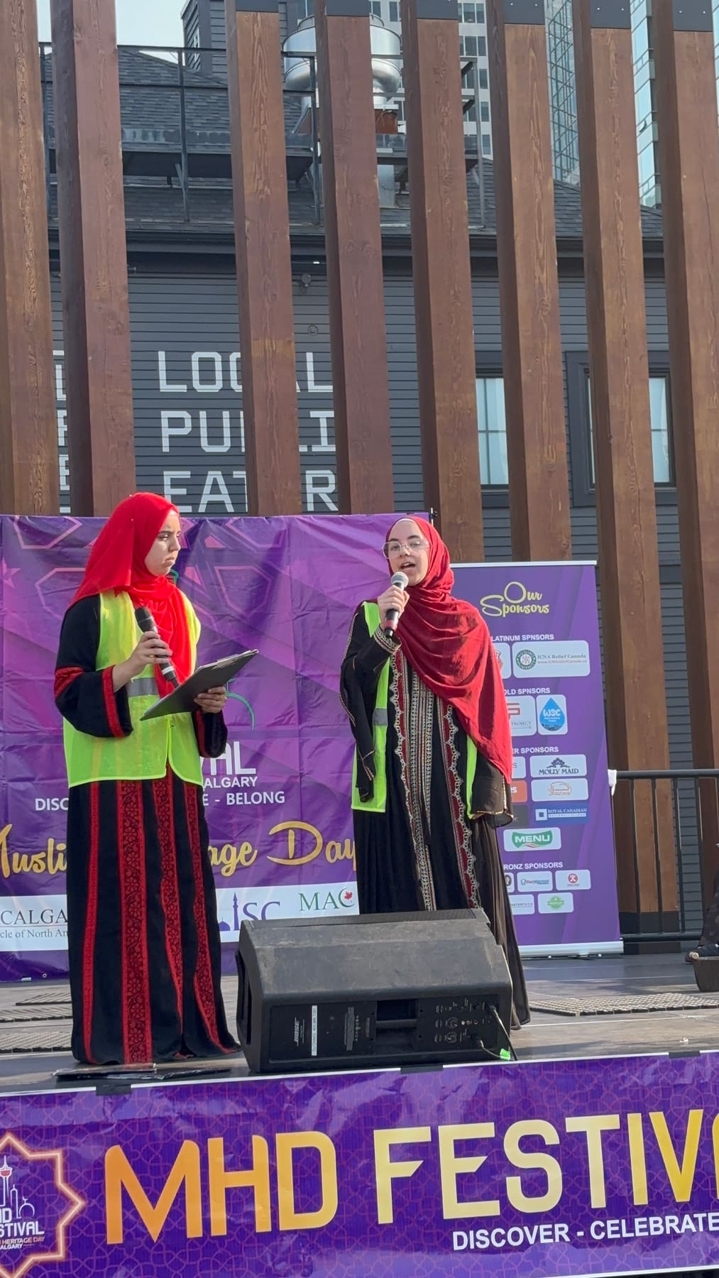 Two hosts with microphones on the Muslim Heritage Day festival stage