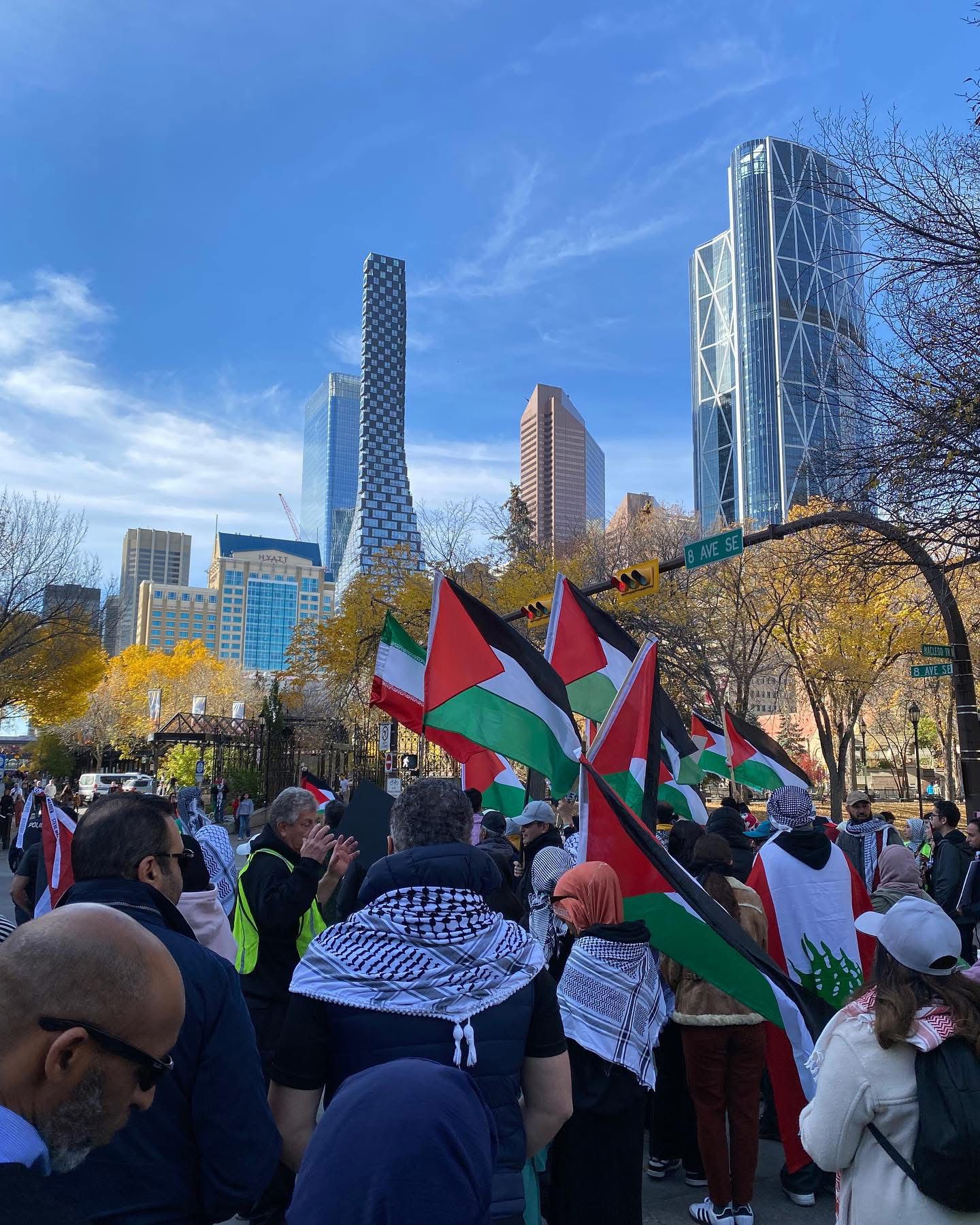 Crowd with Palestinian flags gathered beneath the downtown Calgary skyline